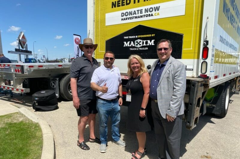 Des employés de Maxim Truck & Trailer ou de Harvest Manitoba devant une remorque.