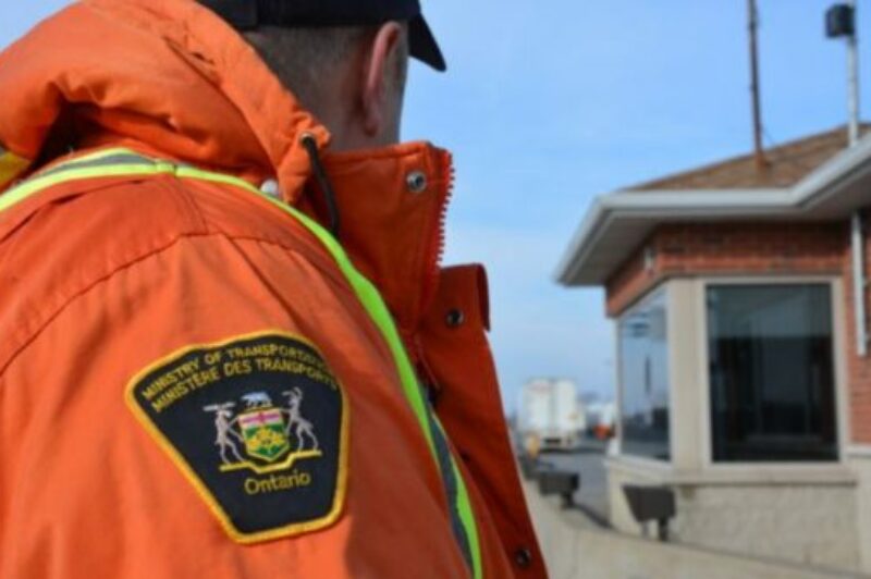 Un contrôleur routier avec un manteau orange.