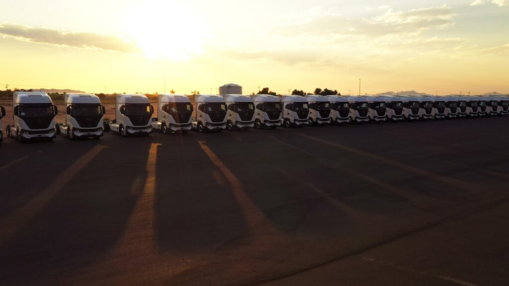 Rangée de camions Nikola Tre à batteries au soleil couchant.