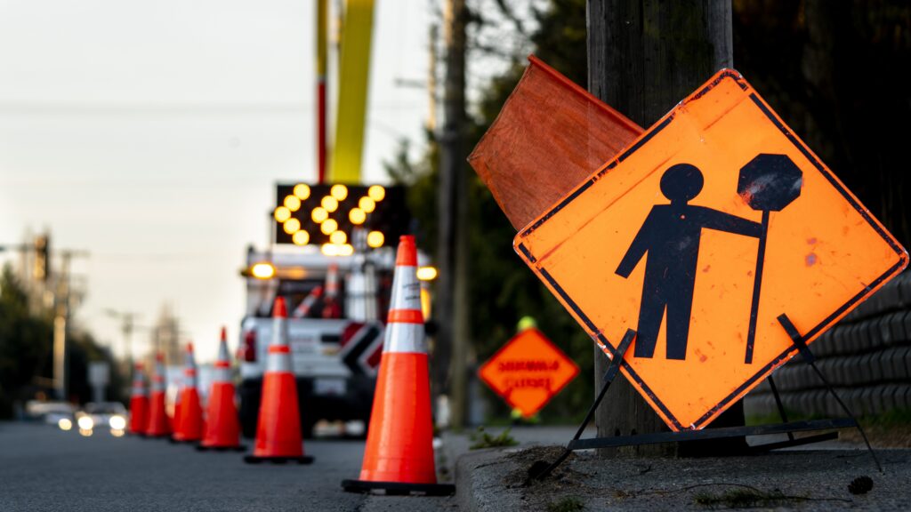 Panneau de signalisation orange et cônes oranges qui indiquent des travaux routiers.