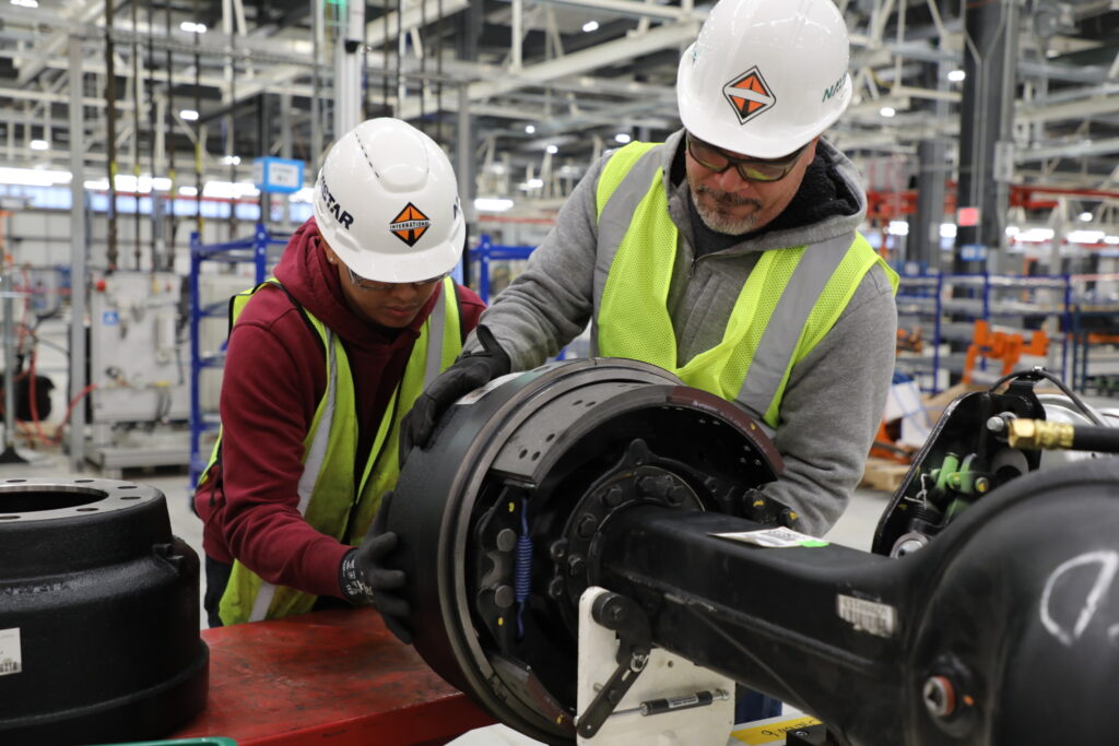 Ouvriers Navistar terminant l’assemblage d’un bout d’essieu moteur en usine.