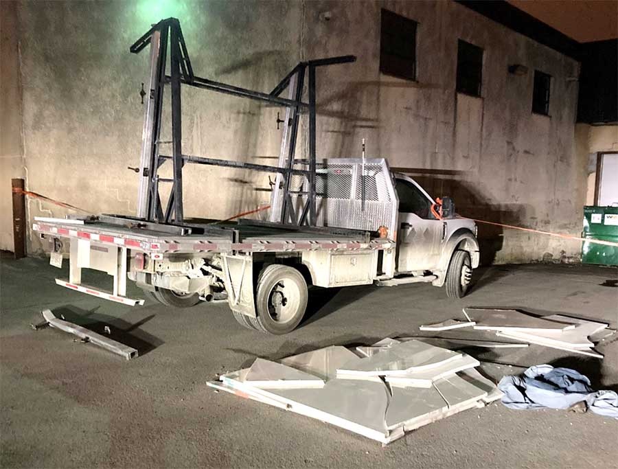 Camion plateforme de poids moyen avec dalles de pierre brisées au sol.