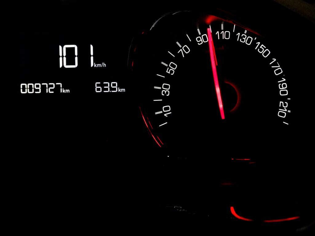 Gros plan d’un indicateur de vitesse à 101 km/h, illuminé dans le noir.