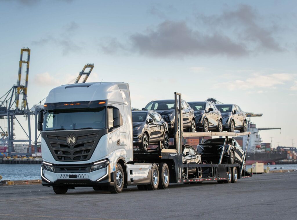 Camion Nikola attelé à une remorque pleine de voitures Nissan