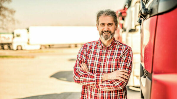 Front view of mature truck driver looking at camera with hands crossed. alternate text for this image