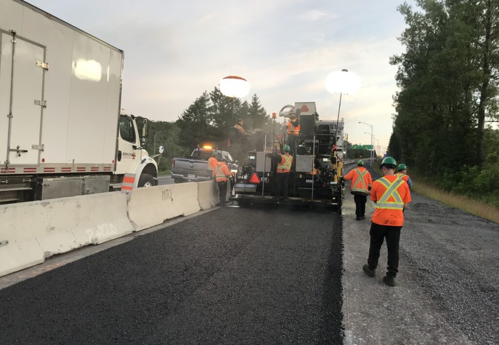 Travailleurs avec machinerie de pavage, camion et pick-up