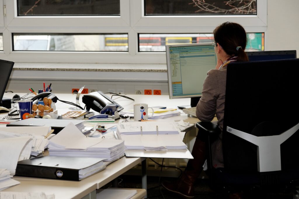 Dame vue de dos à son bureau travaille à l’ordinateur