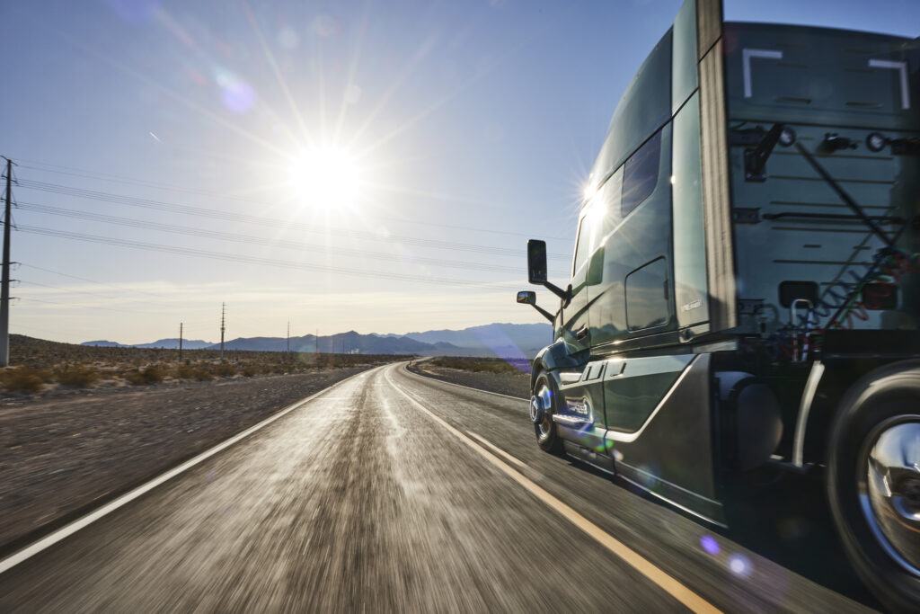 Camion vu de ¾ arrière qui roule sous un soleil de plomb.