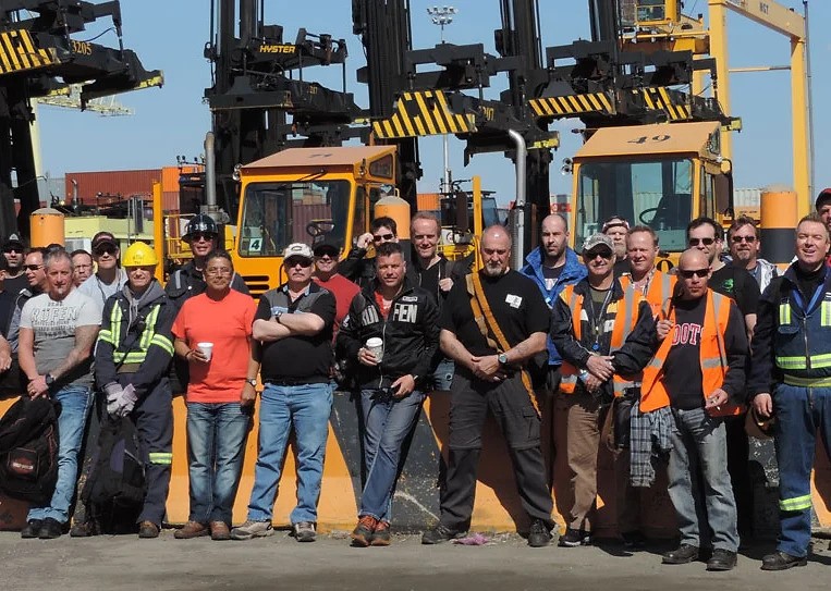 Groupe de débardeurs du port de Montréal à l’extérieur, devant de la machinerie