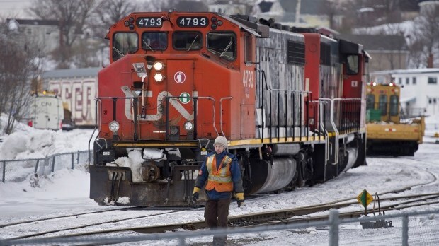 Travailleur en dossard devant une locomotive du CN en décor hivernal