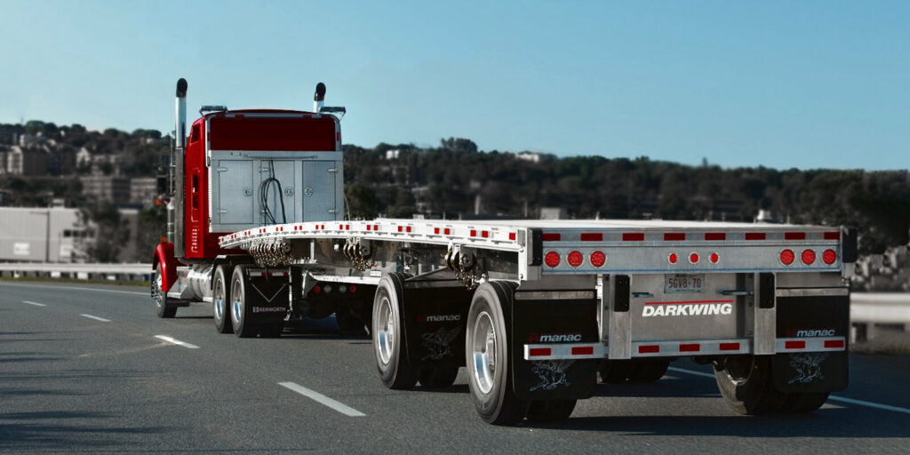 Vue de l’arrière d’un camion tractant une remorque plateforme Manac