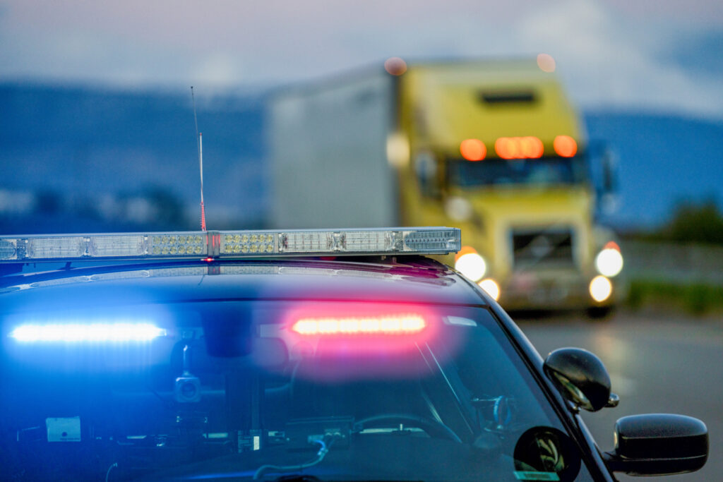 Flashs de police rouges et bleus en avant-plan, camion Volvo jaune en arrière-plan