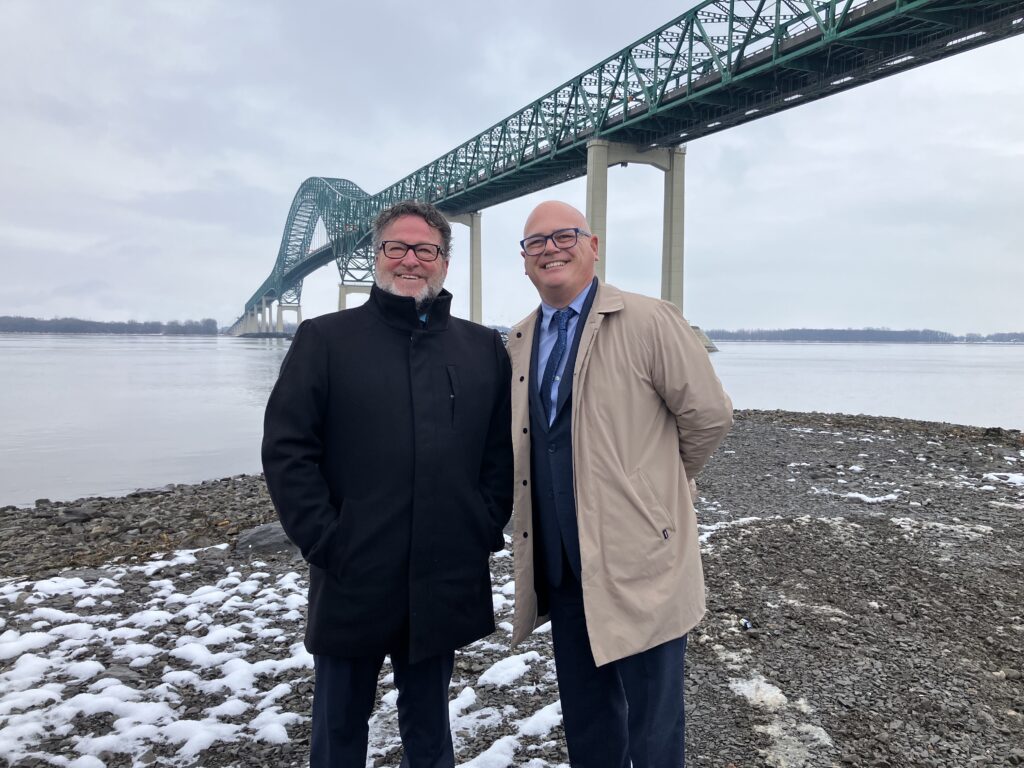 Les ministres québécois Jonatan Julien et Donald Martel avec le pont Laviolette en arrière-plan.
