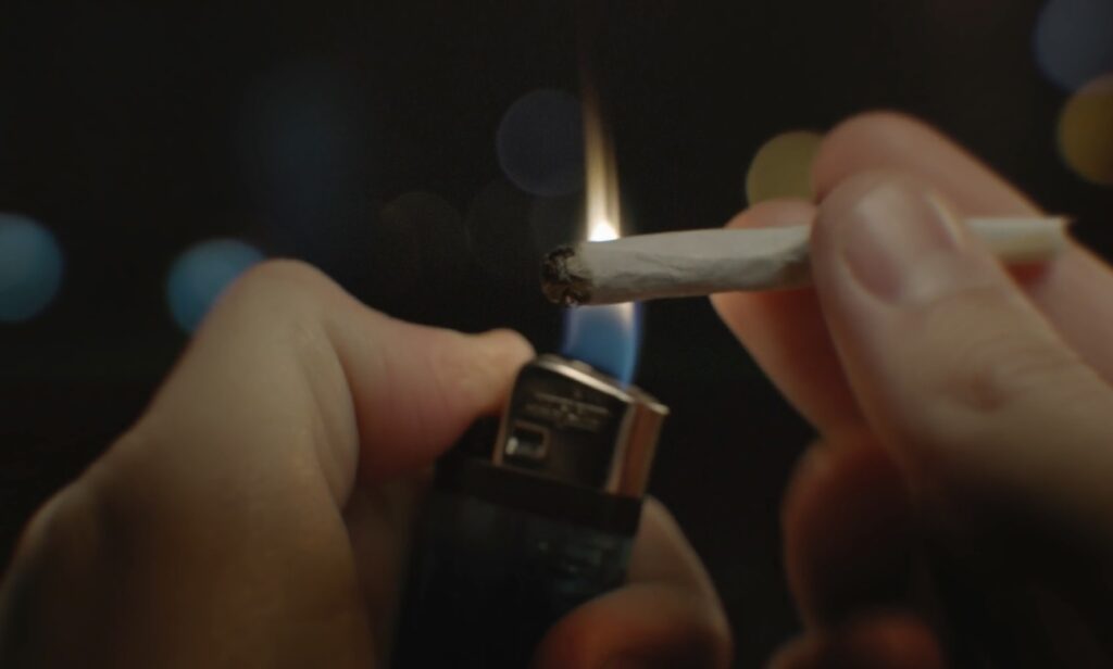 Gros plan d’un briquet qui allume un joint de cannabis