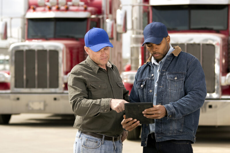 Deux chauffeurs étudient une tablette devant leurs camions