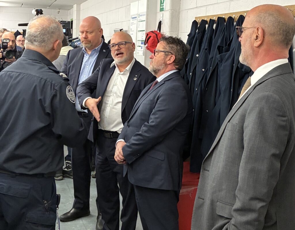 Faisant mine de tenir une arme à feu avec sa main, le ministre des Transports du Québec, Jonatan Julien, discute avec un instructeur de l’École nationale de police. À sa droite, Ian Lafrenière, ministre de la Sécurité publique