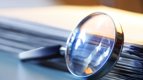Magnifying Glass Leaning Against Stack Of Papers alternate text for this image