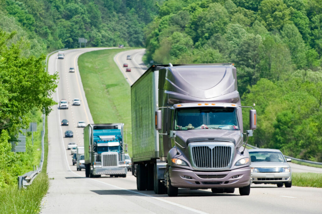 Camions et voitures vus de face grimpent une pente sur l’autoroute