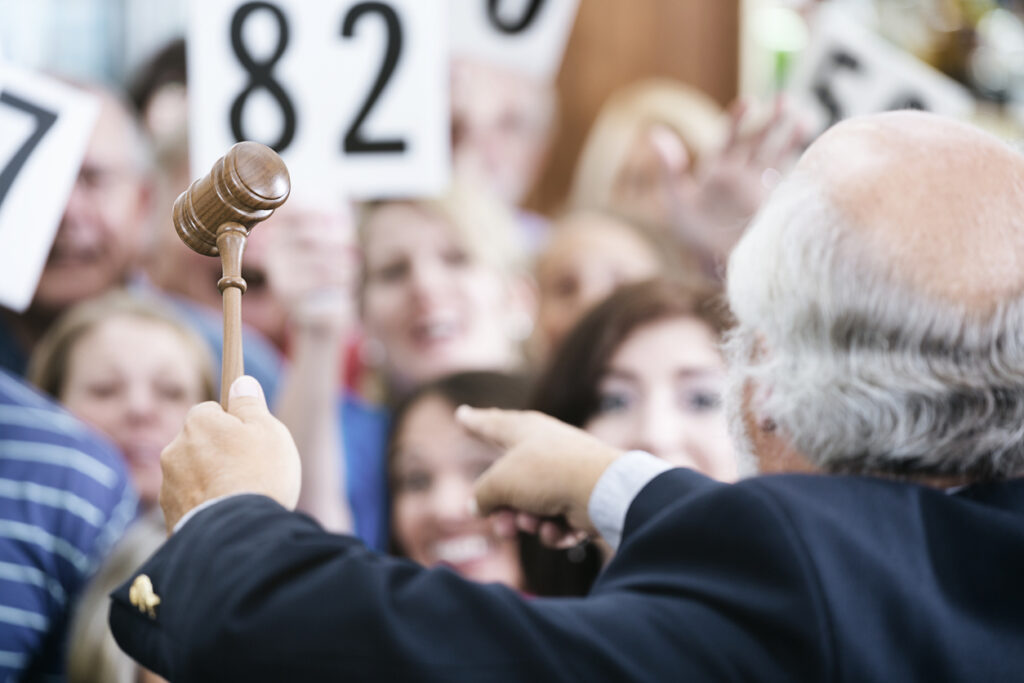 Encanteur vu de dos avec acheteurs qui brandissent leur numéro d’acquéreur