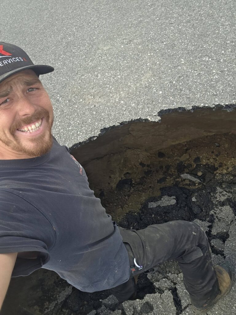 Homme se tient dans un trou de la 117 pour en démontre la profondeur.