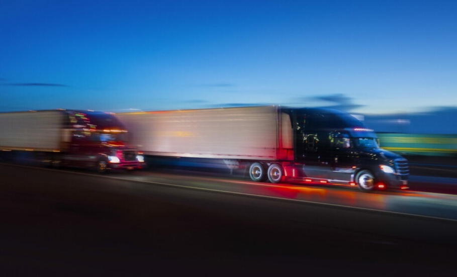 Deux camions semblent se faire la course sur une autoroute, la nuit