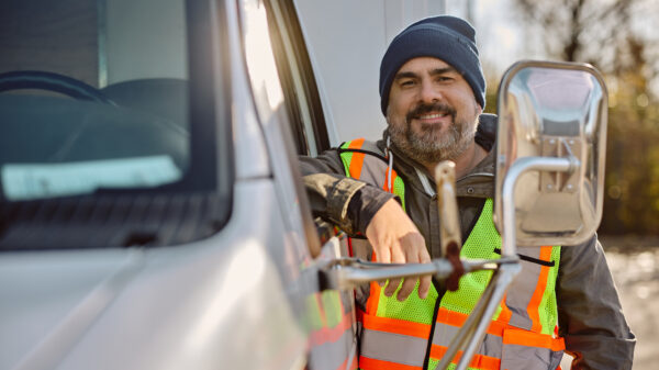 Portrait of happy truck driver by his vehicle looking at camera. alternate text for this image
