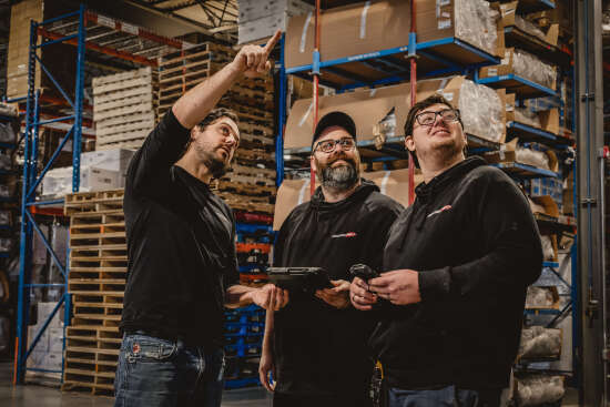Trois hommes discutent dans un entrepôt de Logistique CAF