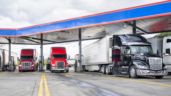 Long haulers big rigs semi trucks with semi trailers fuel tanks with diesel standing on the gas station on the truck stop alternate text for this image