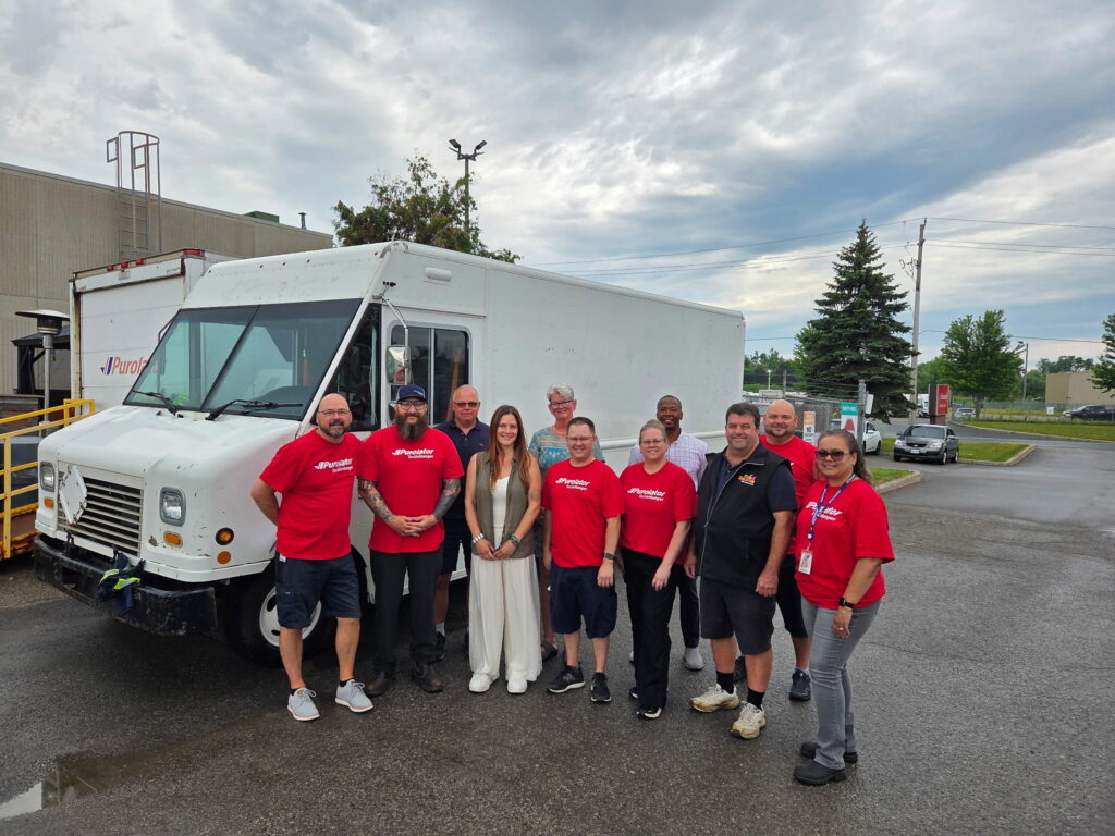Groupe d’employés Purolator devant un camion de livraison donné à une banque alimentaire