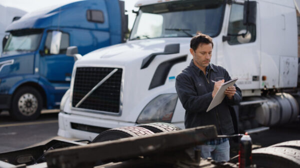 Truck driver inspecting a semi-truck trailer in a parking lot alternate text for this image