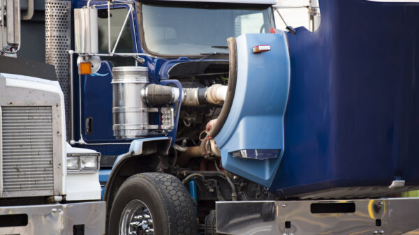 Blue big rig semi truck with open hood standing on the parking lot for repair engine and service work alternate text for this image
