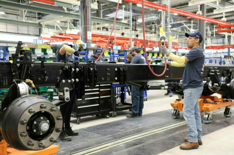 Ouvriers travaillent sur un châssis de camion dans une usine International