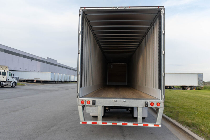 Vue arrière d’une remorque sèche avec les portes ouvertes dans une cour de camionnage