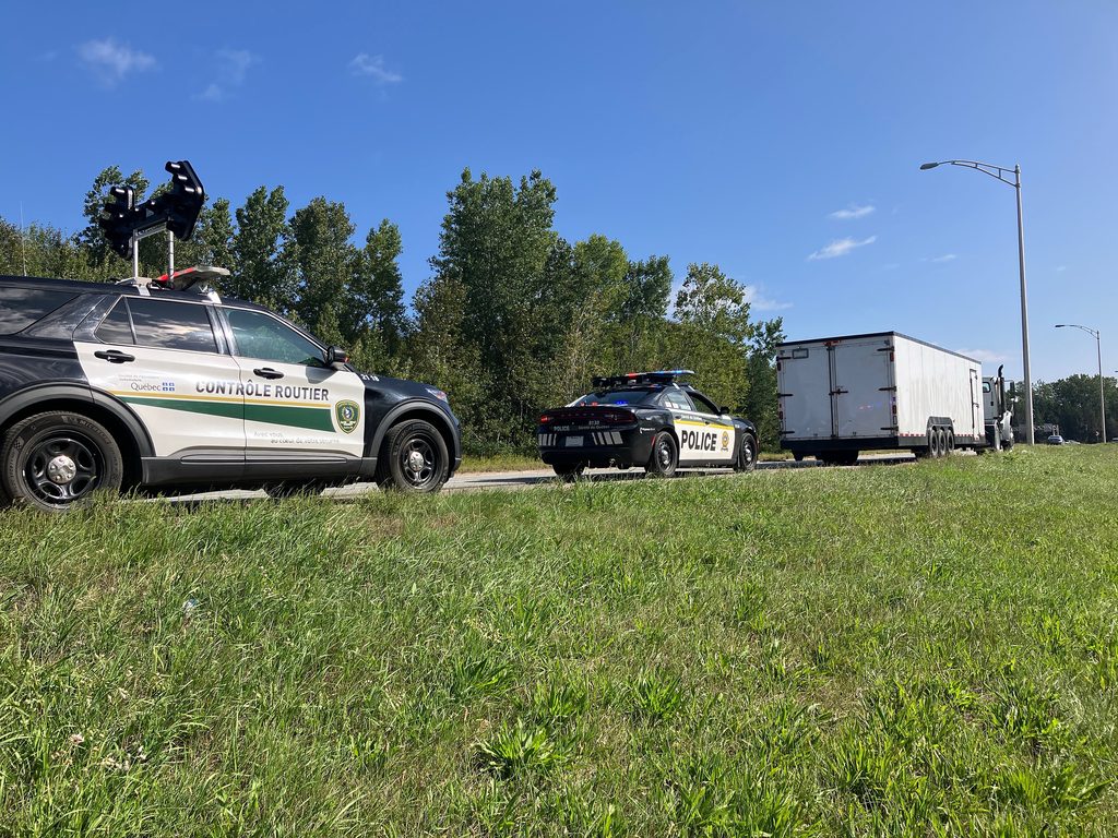 Voiture de contrôleurs routiers et de la police de la SQ derrière un camion intercepté