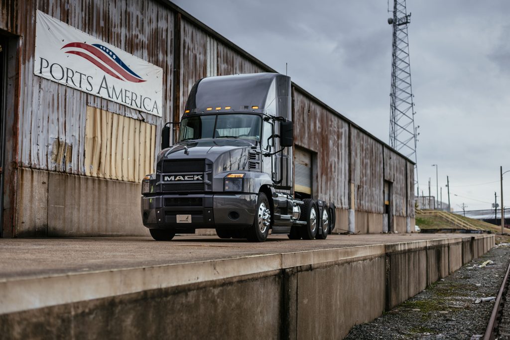 Mack Anthem devant un entrepôt près d’une voie ferrée